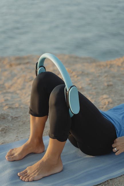 Person peacefully meditating on a yoga mat outdoors near water at sunrise